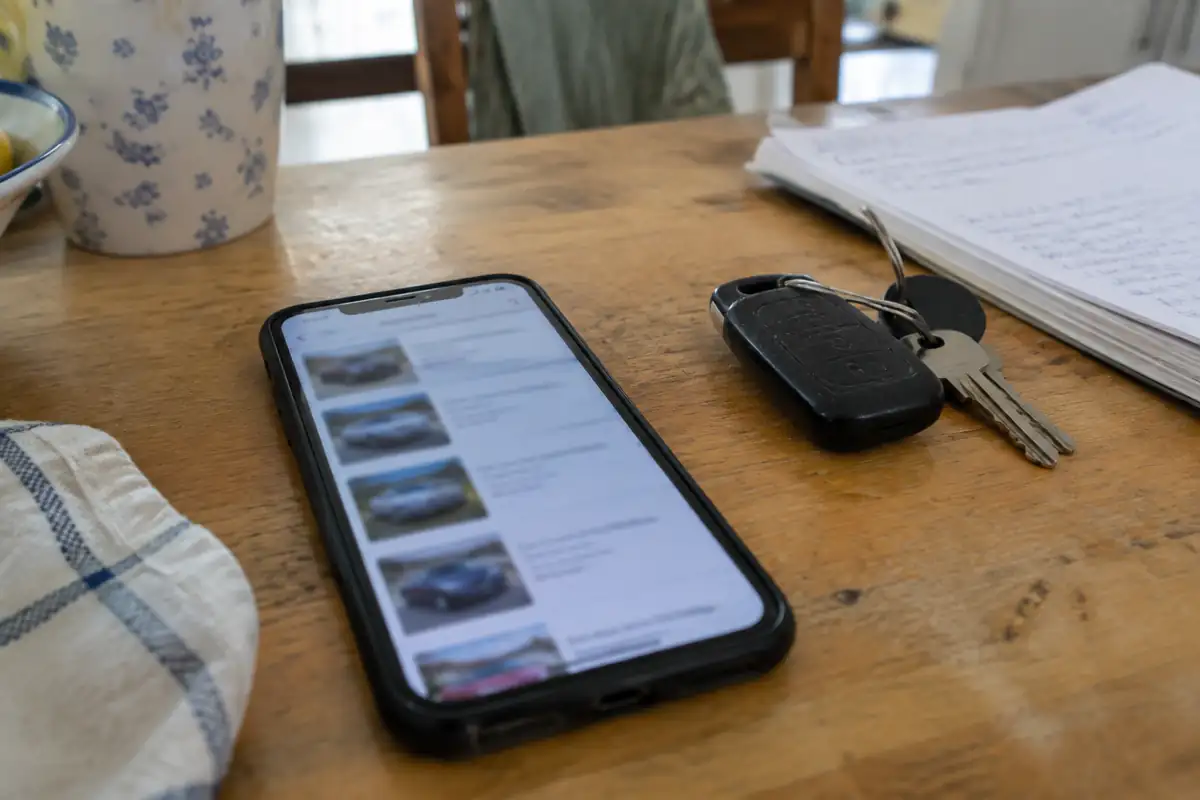 Téléphone posé sur une table affichant une annonce de véhicule d'occasion, à côté de clés de voiture
