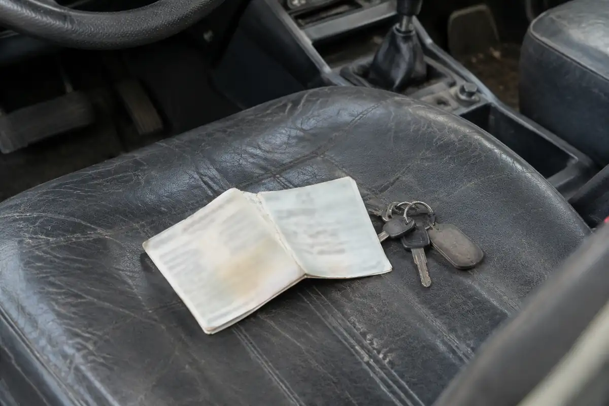 Certificat d'immatriculation plié et clés posés sur le siège d'une voiture ancienne