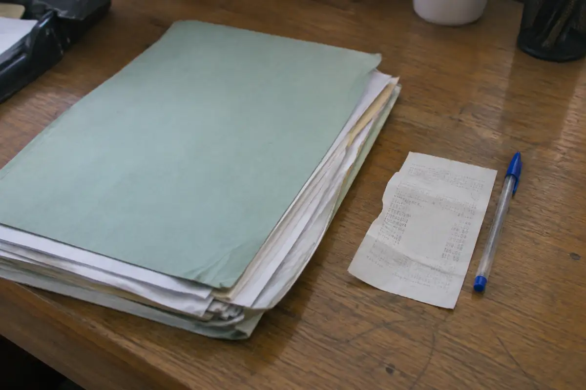 Dossier de pièces et bulletin de pesée posés sur un bureau à côté d'un stylo